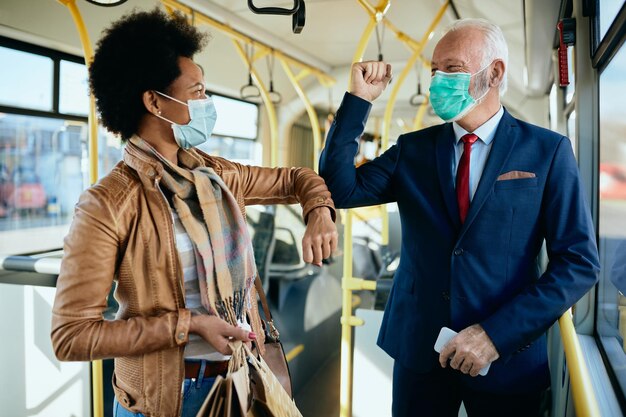 Gelukkig volwassen zakenman elleboog stoten met Afro-Amerikaanse vrouw in een bus