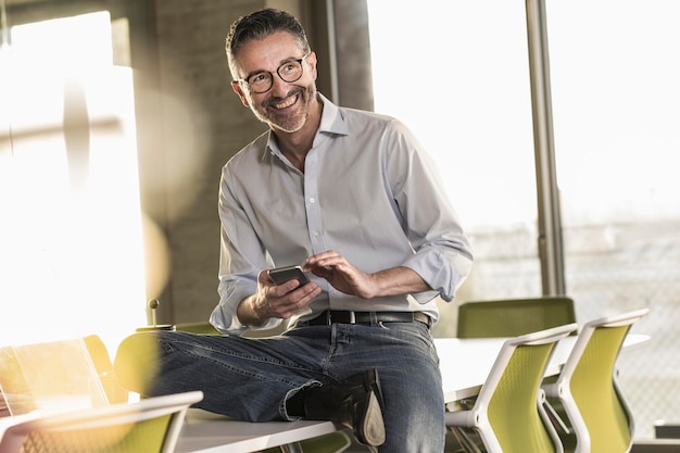 Gelukkig volwassen zakenman met mobiele telefoon in office