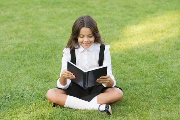 Gelukkig voorschoolse meisje met boek in schoolplein terug naar school hardwerkend kind met boek concept van onderwijs en lezen ontwikkeling van de verbeelding schattig meisje boek gelezen