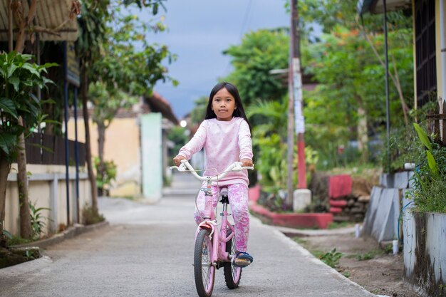 Gelukkig vrolijk Aziatisch kindmeisje dat een fiets berijdt