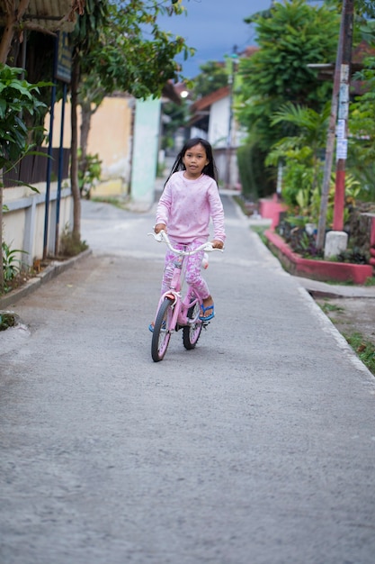 Gelukkig vrolijk Aziatisch kindmeisje dat een fiets berijdt