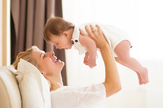 Gelukkig vrolijk familieconcept. Moeder en baby van drie maanden zoenen, lachen en knuffelen, close-up portret