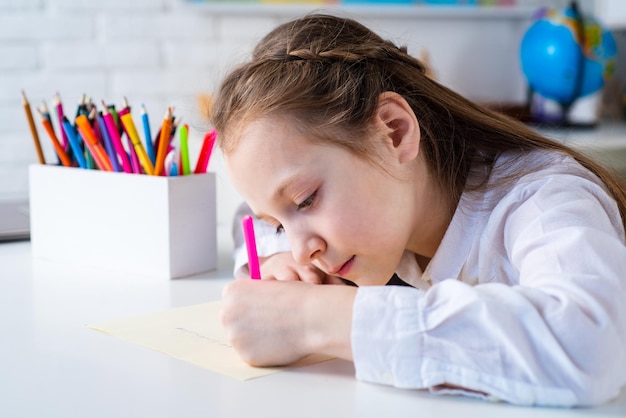 Gelukkig vrolijk kind meisje tekenen Creativiteit concept Schattig kind tekenen met viltstift zittend aan tafel