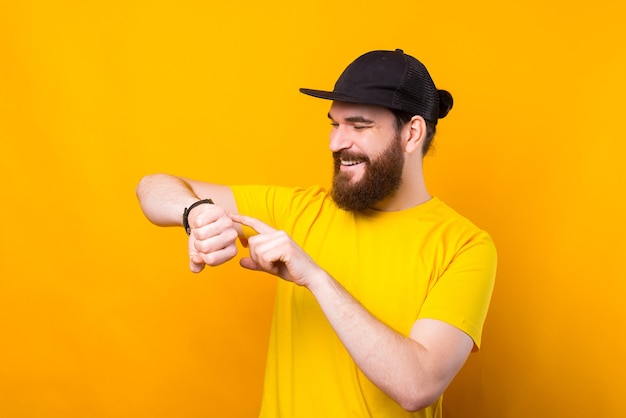 Gelukkig vrolijke bebaarde hipster man met smartwatch op geel