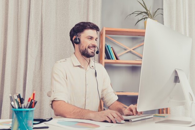 Gelukkig vrolijke jonge werknemer van callcenter in hoofdtelefoons