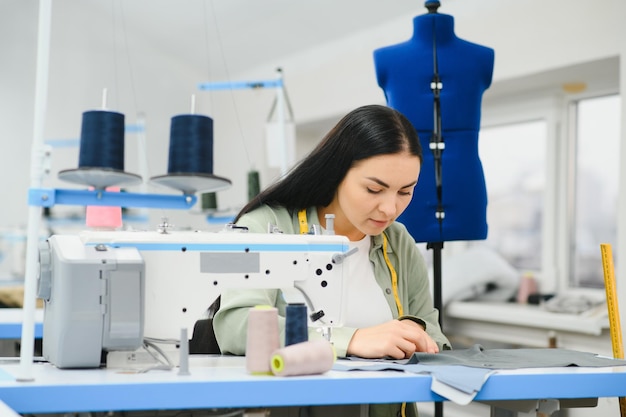 Gelukkig vrouwelijke naaister werken met naaimachine in textielfabriek