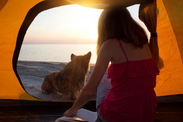 Gelukkig weekend aan zee - meisje met een hond in een tent op het strand bij zonsopgang. Oekraïens landschap aan de Zee van Azov, Oekraïne