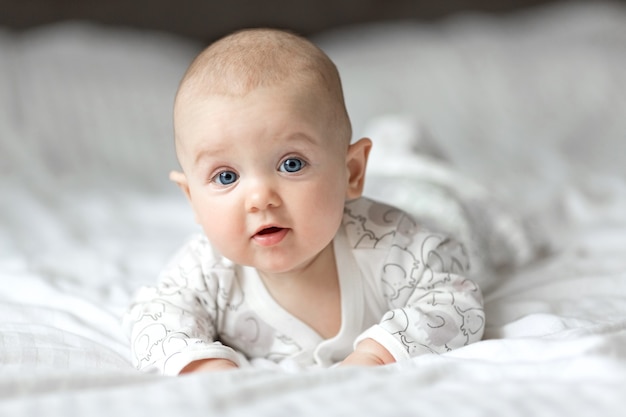 Gelukkig weinig baby camera kijken en glimlachen liggend op het bed