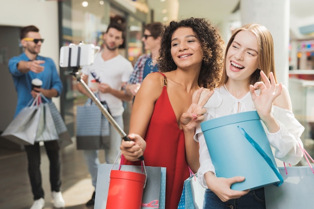 Gelukkig winkelen meisjes nemen selfie samen in het winkelcentrum.