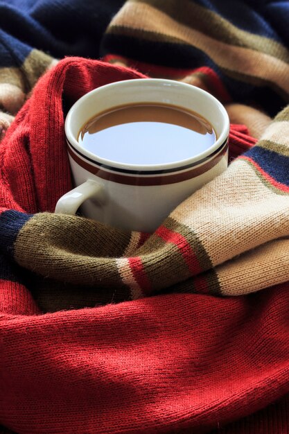 gelukkig winterconcept. kopje koffie op rode trui. over het licht