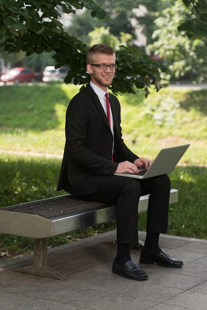 Gelukkig zakenman met behulp van Tablet Pc buiten op een bankje in het park