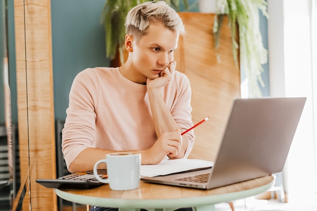 Gelukkig zakenman zit op cafetaria met laptop en smartphone. Zakenman texting op slimme telefoon zittend in een café, werken en e-mail controleren op computer