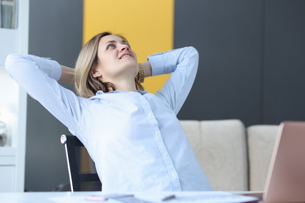 Gelukkig zakenvrouw zit aan haar werktafel en kijkt naar het plafond