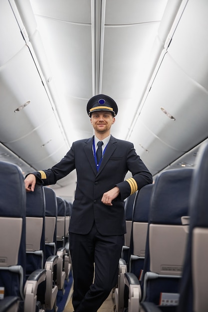 Gelukkig zelfverzekerde blanke piloot in vliegtuigsalon