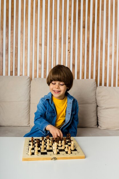 Gelukkig zit kleine blanke jongen met bruin haar op een bank te schaken. kinder ontwikkeling