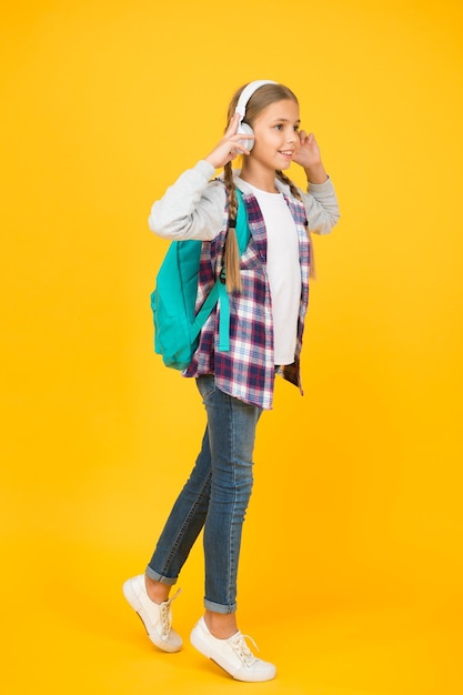 Gelukkig zorgeloos kind. School klassen. Leerling. Modern onderwijs. Energieke vrolijke tiener die muziek luistert. Stijlvol schoolmeisje dat naar school gaat. Meisje modieus meisje met rugzak. Schoolleven.