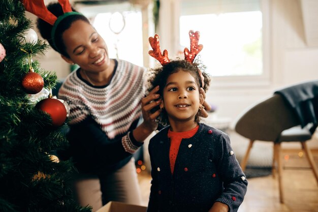 Gelukkig zwart meisje dat plezier heeft met haar moeder terwijl ze zich thuis voorbereidt op kerstmis