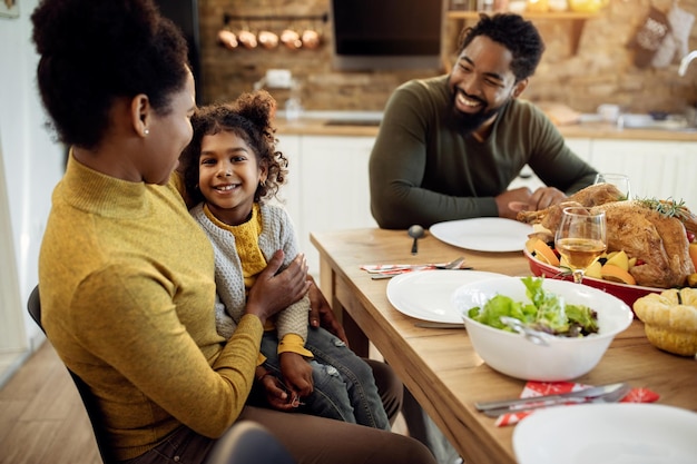 Gelukkig zwart meisje en haar ouders genieten thuis van een thanksgiving-maaltijd