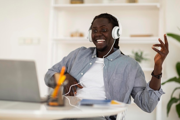 Gelukkig zwarte man in koptelefoon luisteren muziek online met laptop