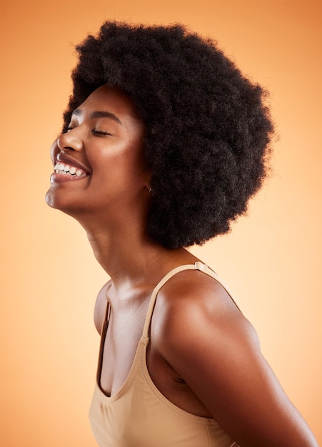 Gelukkig zwarte vrouw cosmetische schoonheid en natuurlijke huidverzorging of haarverzorging wellness Afrikaans meisje huid gezondheid afro leuk haar en gezond geluk gloed levensstijl in studio tegen oranje achtergrond