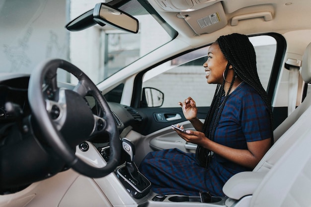 Gelukkig zwarte vrouw met een telefoon in de auto