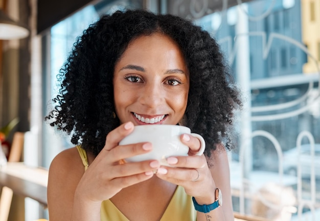 Gelukkig zwarte vrouw portret en ontspannen in coffeeshop restaurant of bistro voor lunch latte en glimlach Face café en jonge vrouw genieten van kopje thee, drinken cappuccino en breken alleen met geluk