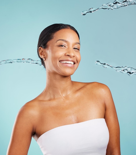 Gelukkig zwarte vrouw portret en waterplons in studio voor het reinigen van cosmetica op blauwe achtergrond Gezicht van vrouwelijk model douchedruppels en schoonheid voor gezonde huidverzorging, wellness en gezichtsesthetiek