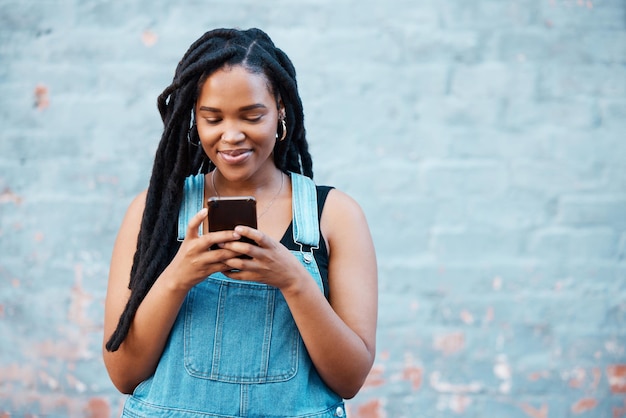 Gelukkig zwarte vrouw typen op smartphone op sociale media marketing reclame of mobiele app op blauwe muur achtergrond mockup Gen z tiener met mobiel netwerken online chat of check notificatie