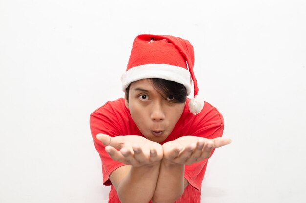 gelukkige aantrekkelijke Aziatische man in rode kerstkleding die met de vinger wijst en iets presenteert.