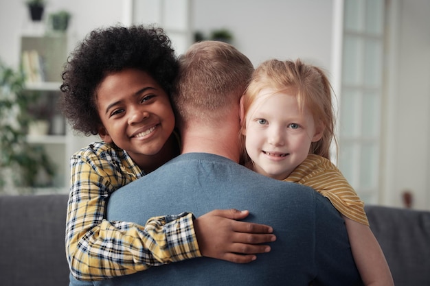 Foto gelukkige adoptiekinderen die vader omhelzen