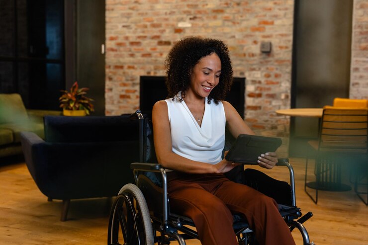 Foto gelukkige afro-amerikaanse casual zakenvrouw in een rolstoel met een tablet op kantoor. casual office, handicap, inclusiviteit, communicatie, zaken, professioneel en werk, ongewijzigd.