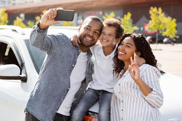 Gelukkige Afro-Amerikaanse familie die selfie maakt met gloednieuwe auto