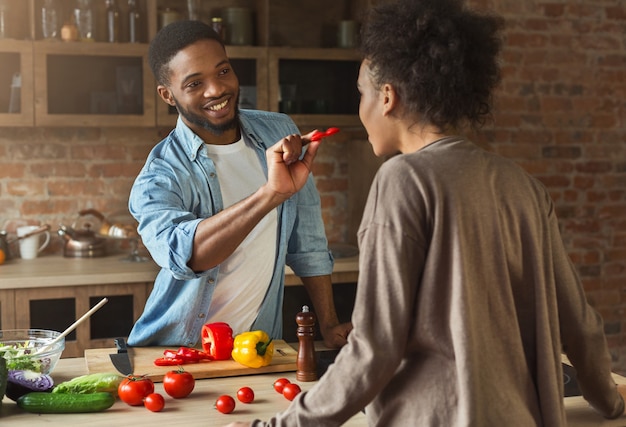 Gelukkige Afro-Amerikaanse familie in de keuken. Zwart koppel koken in loft interieur