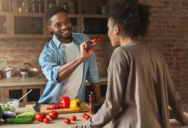 Gelukkige Afro-Amerikaanse familie in de keuken. Zwart koppel koken in loft interieur