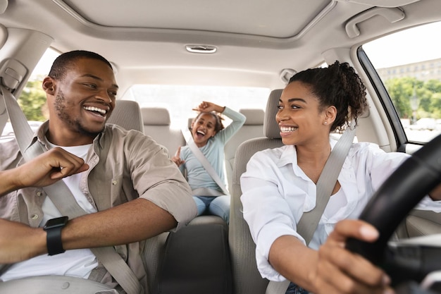 Gelukkige Afro-Amerikaanse familie rijden nieuwe auto zingen met plezier