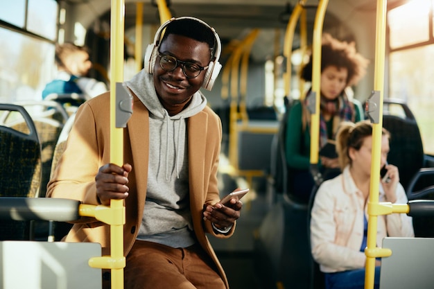 Gelukkige afro-amerikaanse man die een koptelefoon draagt tijdens het reizen met de bus