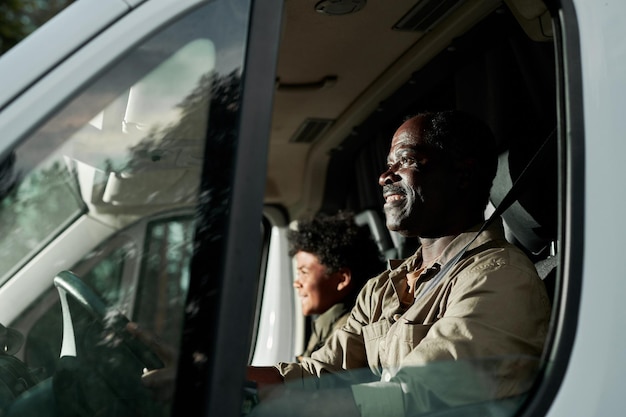 Gelukkige afro-amerikaanse vader die met zijn zoon in een busje rijdt