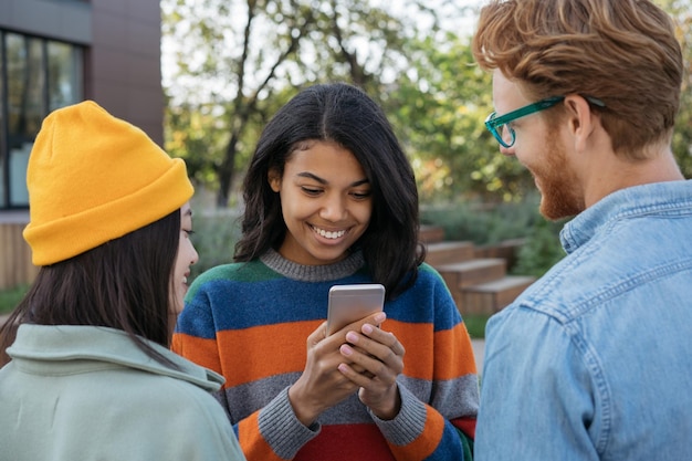 Gelukkige Afro-Amerikaanse vrouw die mobiele telefoon gebruikt om online eten te bestellen en mobiel spel te spelen