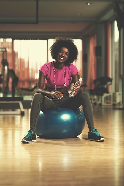 gelukkige afro-amerikaanse vrouw met een krullend afro-kapsel in een sportschool die ontspant na pilatestraining