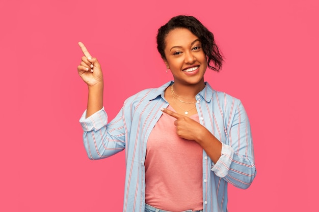 Gelukkige Afro-Amerikaanse vrouw wijst met haar vinger omhoog.
