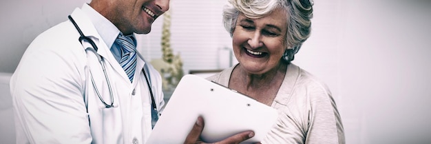 Foto gelukkige arts en patiënt bespreken rapporten in de kliniek