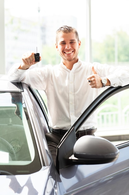 Gelukkige autobezitter toont duimen en zijn nieuwe autosleutel