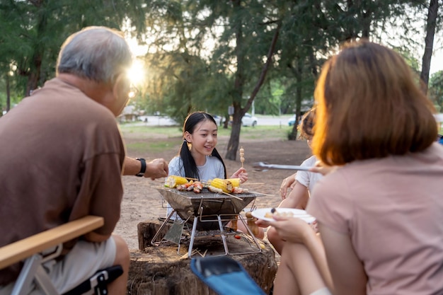 Gelukkige aziatische familie die samen barbecue heeft. gegrilde bbq koken voor het diner tijdens het kamperen op het zomerstrand.