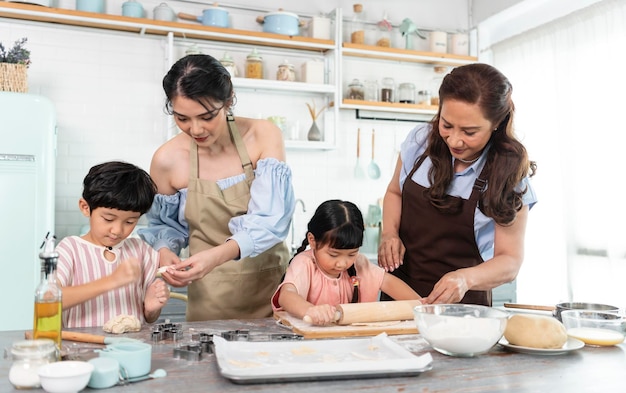 Gelukkige Aziatische familie die voorbereidingsdeeg maakt en koekjes thuis in keuken bakt Geniet van familie