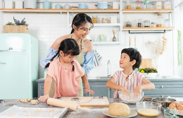 Gelukkige aziatische familie die voorbereidingsdeeg maakt en koekjes thuis in keuken bakt geniet van familie