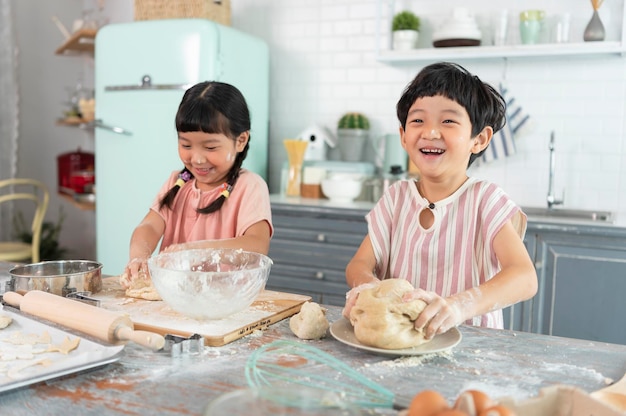 Gelukkige Aziatische familie grappige kinderen bereiden de deegkoekjes voor in de keuken