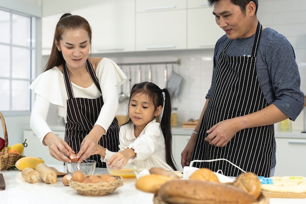 gelukkige Aziatische familie met dochter die deeg maakt en bakkoekjes voorbereidt