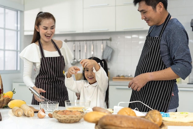 Gelukkige Aziatische familie met dochter die deeg maakt om koekjes te bakken Dochter helpt ouder bij het voorbereiden van het bakgezin Familieconcept