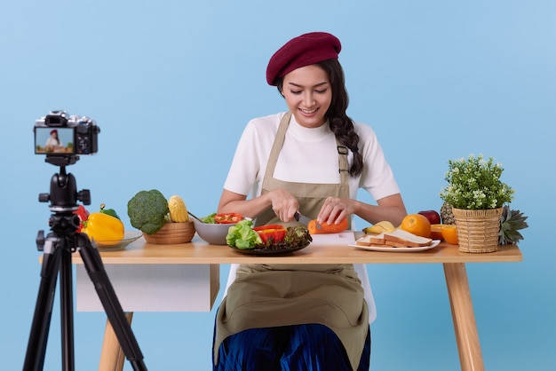 Foto gelukkige aziatische jonge vrouw in mode-look stijl en video schieten met camera koken eten gezond is blogger presenteren voor sociale mensen. haar is influencer in sociale online.