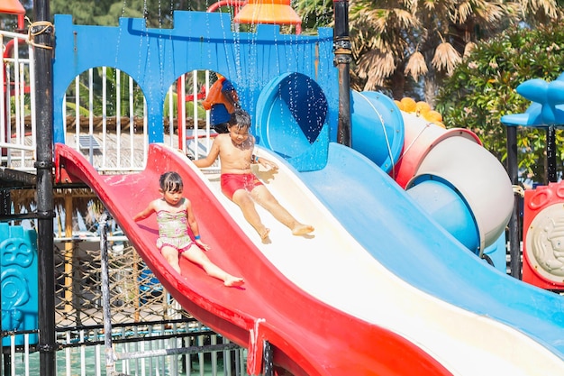 Foto gelukkige aziatische kinderen broers en zussen zwemmen en spelen waterschuifbalk speelgoed in het blauwe zwembad